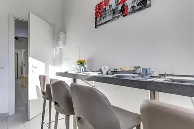 a kitchen with white chairs and a bar with a counter at Voyager House Termini - Home and More in Rome