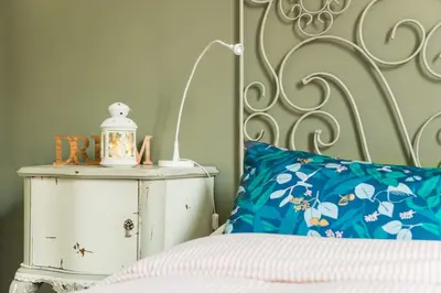 a bed with a blue pillow next to a white nightstand at New Suite Amèlie in Rome