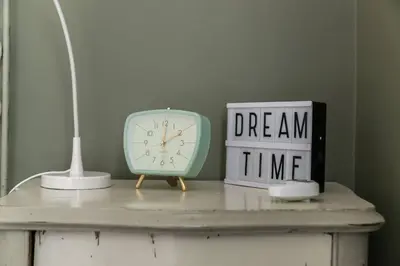 a table with a clock and a book and a lamp at New Suite Amèlie in Rome
