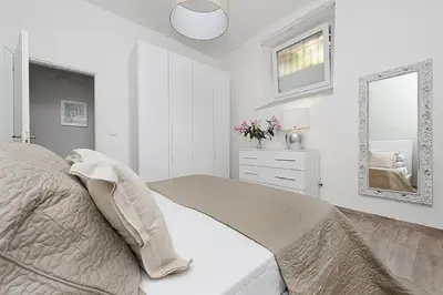 a white bedroom with a bed and a mirror at BMGA l Mon Amour San Giovanni Apartment in Rome