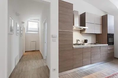 a kitchen with white walls and wooden cabinets at BMGA l Mon Amour San Giovanni Apartment in Rome