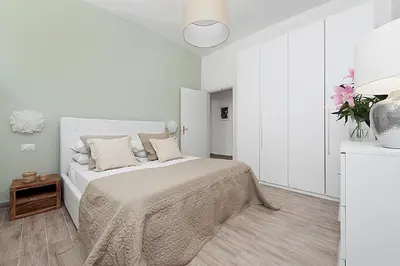 a white bedroom with a bed and a table at BMGA l Mon Amour San Giovanni Apartment in Rome