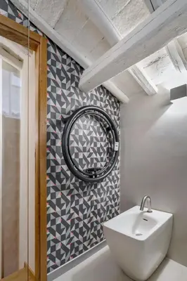a bathroom with a white sink and a patterned wall at Flat PIAZZA DEL POPOLO in Rome