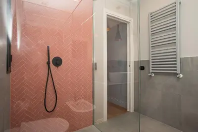 a bathroom with a shower with pink tile at LikeYourHome, 80 sq m luxury apartment with Jacuzzi, in Trastevere district in Rome