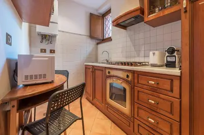 a kitchen with wooden cabinets and a table with a microwave at Amazing studio in Campo de Fiori - FromHometoRome in Rome
