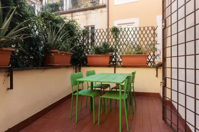 a green table and chairs on a balcony with plants at Apartment with terrace near Piazza Navona - FromHometoRome in Rome