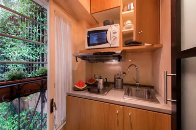 a kitchen with a sink and a microwave next to a window at The Inn at the Spanish Steps Luxury Collection - Premium Studio Room in Rome