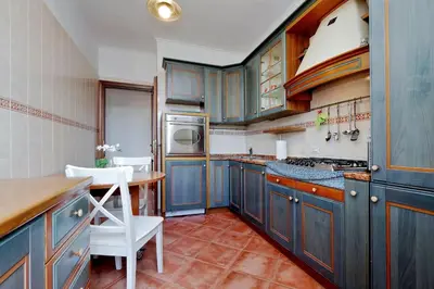 a kitchen with blue cabinets and a table and chairs at Colosseo Sunset Apartment in Rome