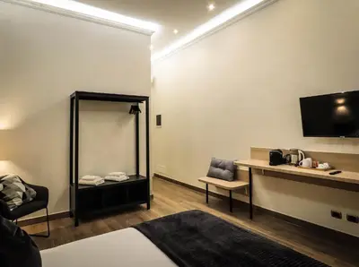 a room with a bed and a desk and a tv at My Maison 70 Guest House in Rome