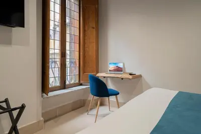 a bedroom with a blue chair and a desk with a laptop at Campo de' Fiori 34 in Rome
