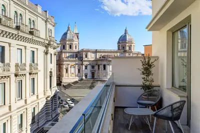 a balcony with two chairs and a view of the buildings at DoubleTree By Hilton Rome Monti in Rome