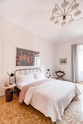 a white bedroom with a large bed and a chandelier at Casa di Artemisia in Rome