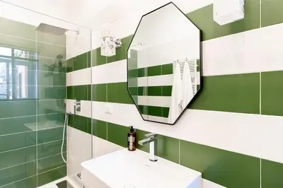 a green and white bathroom with a sink and a mirror at Casa di Artemisia in Rome