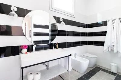 a white bathroom with black and white tiles at Casa di Artemisia in Rome