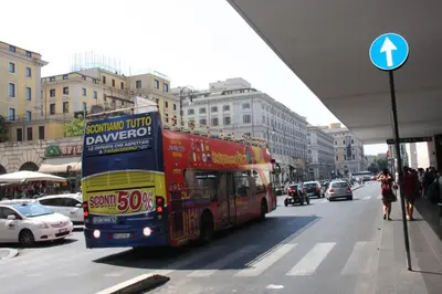 a red double decker bus driving down a city street at Roma Castle Termini in Rome