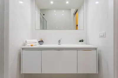 a white bathroom with a sink and a mirror at Design Suite Trevi Fountain in Rome