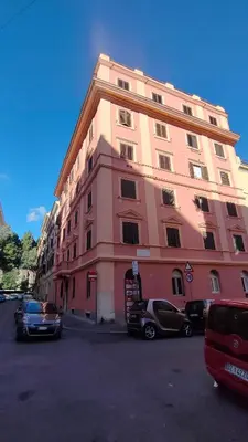 a pink building with cars parked in front of it at Il nido al Colosseo in Rome
