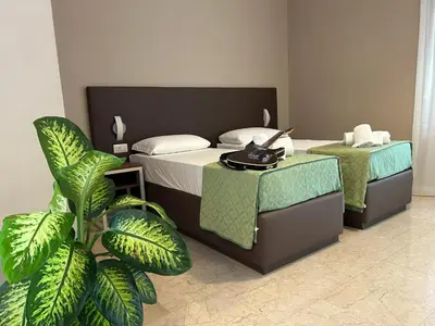 a hotel room with two beds and a plant at Villa Angeli in Rome
