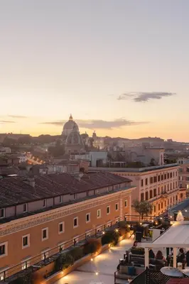 a rooftop patio with chairs and tables with a view of the city at Navona Queen Rooftop in Rome