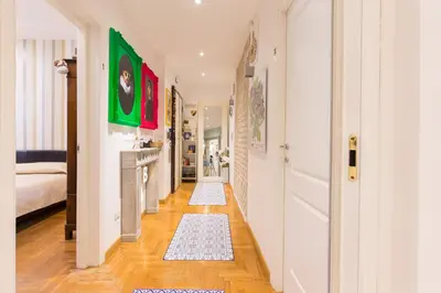 a hallway with white walls and wood floors with rugs at Vatican Rooms Irene in Rome