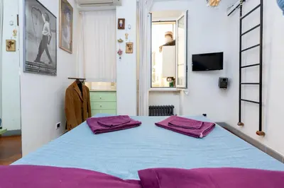 a bedroom with a blue bed with purple pillows on it at DomusAmor Navona in Rome