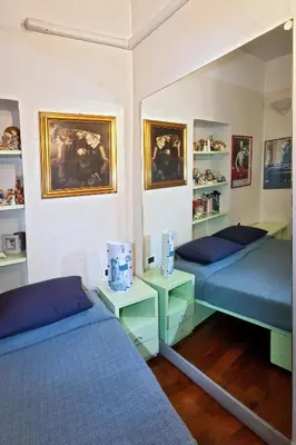 a room with two beds and shelves with paintings at DomusAmor Navona in Rome