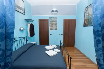 a blue bedroom with a bed with towels on it at DomusAmor Colosseo in Rome
