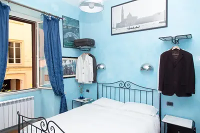 a bedroom with blue walls and a bed and a window at DomusAmor Colosseo in Rome