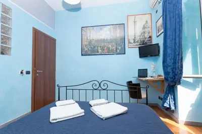 a blue bedroom with a bed with two white towels at DomusAmor Colosseo in Rome