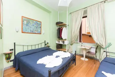 a bedroom with a bed with blue sheets and a window at DomusAmor Colosseo in Rome