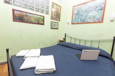 a bedroom with a blue bed with a laptop on it at DomusAmor Colosseo in Rome