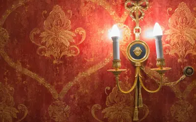 a candle holder with two candles on a red wall at Ripetta Rooms in Rome