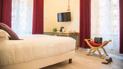 a bedroom with a bed and a chair and a tv at Ripetta Rooms in Rome