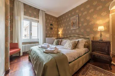 a bedroom with a bed and a chair and a window at Quiet and classic on two floors, by Trevi Fountain - FromHometoRome in Rome