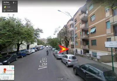a person riding a motorcycle down a city street with a flag at Efeso 19 in Rome