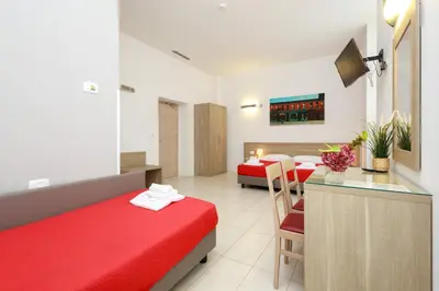 a hotel room with a red bed and a kitchen at San Luigi - Residenza Gemelli in Rome