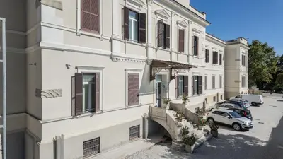an apartment building with cars parked in a parking lot at San Luigi - Residenza Gemelli in Rome