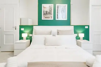 a bedroom with a white bed and green walls at DrsRome - Roman's Ruins Colosseum in Rome