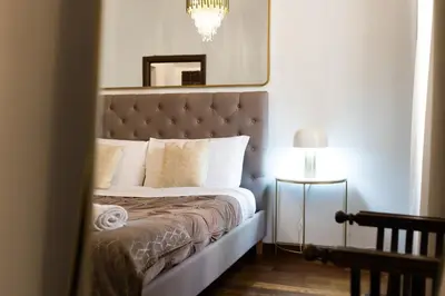 a bedroom with a bed with a mirror and a chandelier at DrsRome - Roman's Ruins Colosseum in Rome