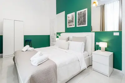 a bedroom with a white bed and green walls at DrsRome - Roman's Ruins Colosseum in Rome