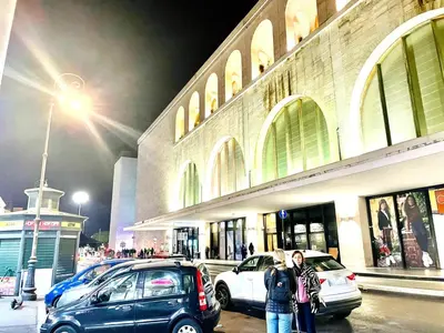 two people standing in front of a building with cars at Rome Place in Rome