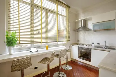 a kitchen with a counter with chairs and a sink at Condotti Corner Apartment Piazza di Spagna in Rome
