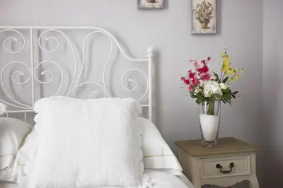 a white bed with a vase of flowers on a table at DD Luxury House in Rome
