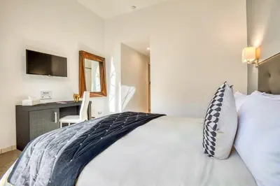 a bedroom with a bed with a desk and a television at Ada Rooms in Rome