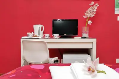 a room with a desk with a computer on a red wall at Affittacamere Alessia&Calliope in Rome