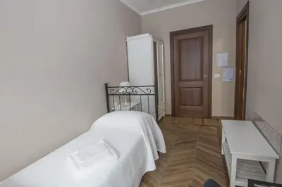 a bedroom with a white bed and a wooden floor at Bed & Breakfast Vacanze Romane in Rome