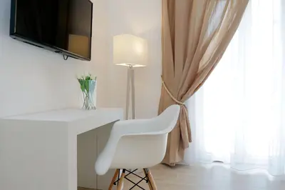 a white chair sitting next to a desk with a television at My Little Holiday in Rome