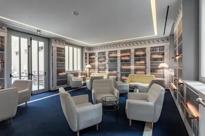 a waiting room with chairs and tables and windows at Room Mate Collection Filippo, Rome-Fontana di Trevi in Rome