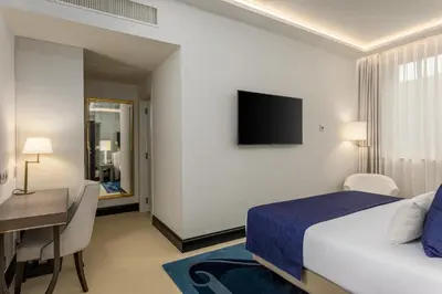 a bedroom with a bed and a desk and a television at Room Mate Collection Filippo, Rome-Fontana di Trevi in Rome
