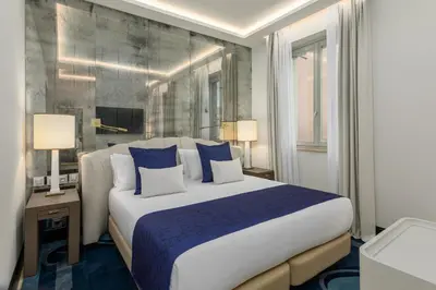 a bedroom with a large bed with blue and white pillows at Room Mate Collection Filippo, Rome-Fontana di Trevi in Rome